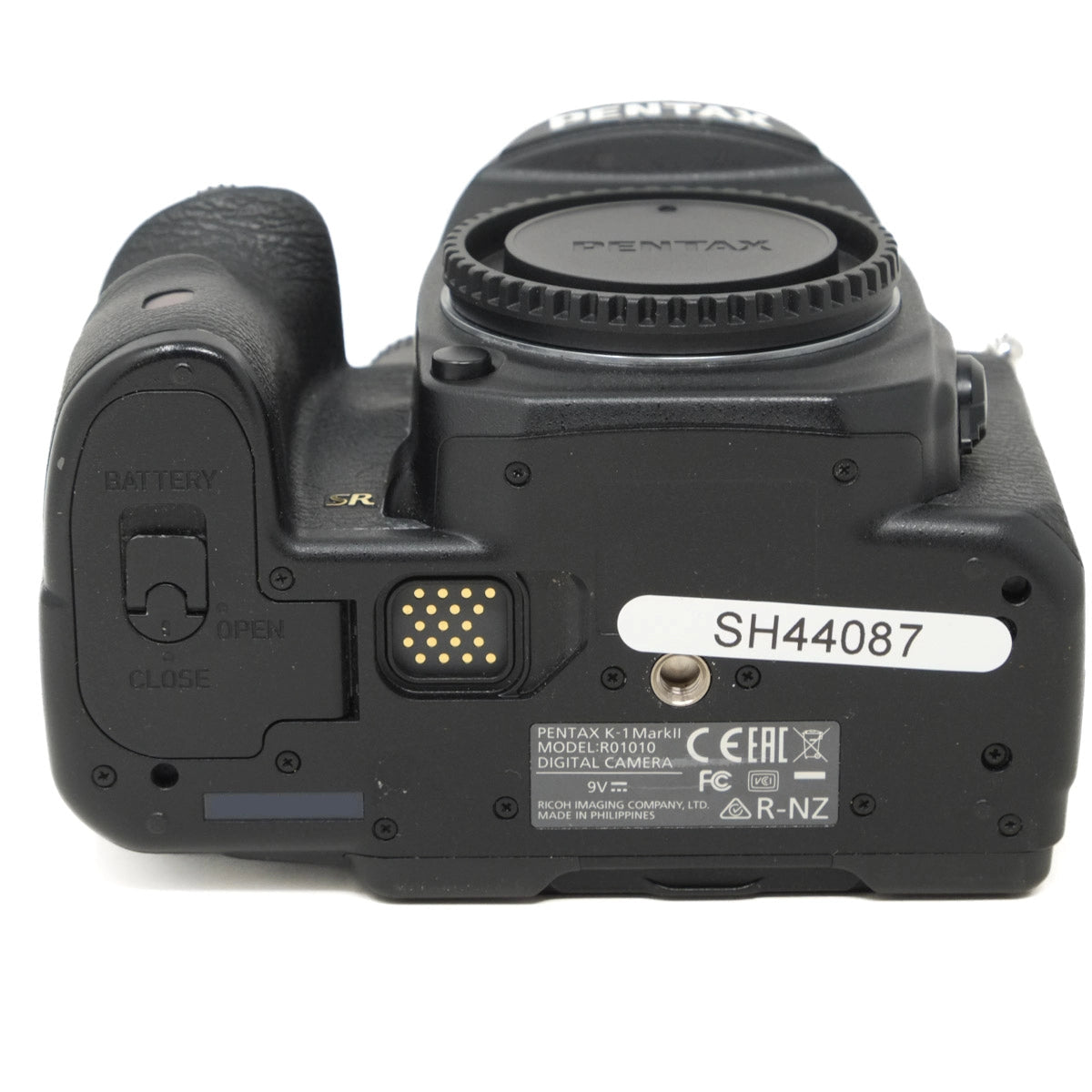 Bottom view of a Pentax digital camera on a white background