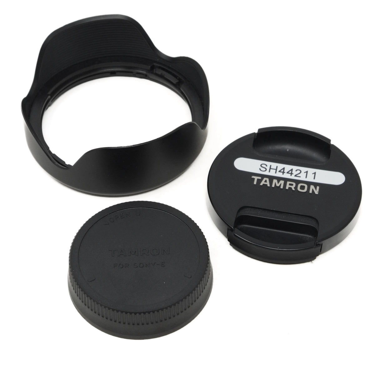 Two black camera lens caps and lens hood with Tamron branding on a white background