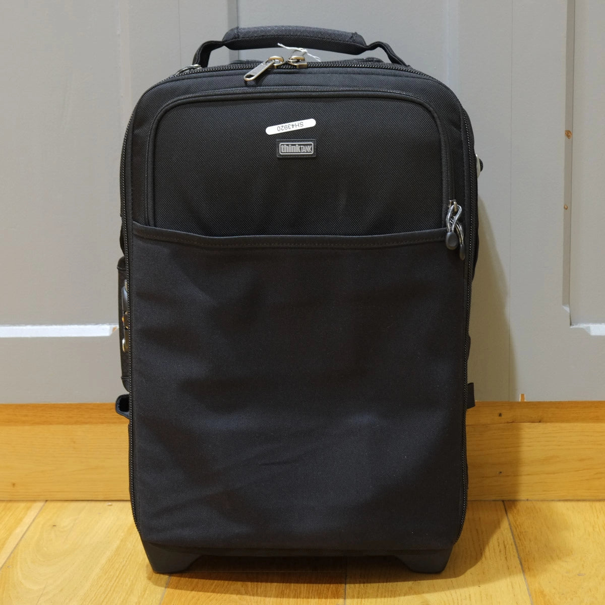 Black suitcase with a visible brand logo on a wooden floor.