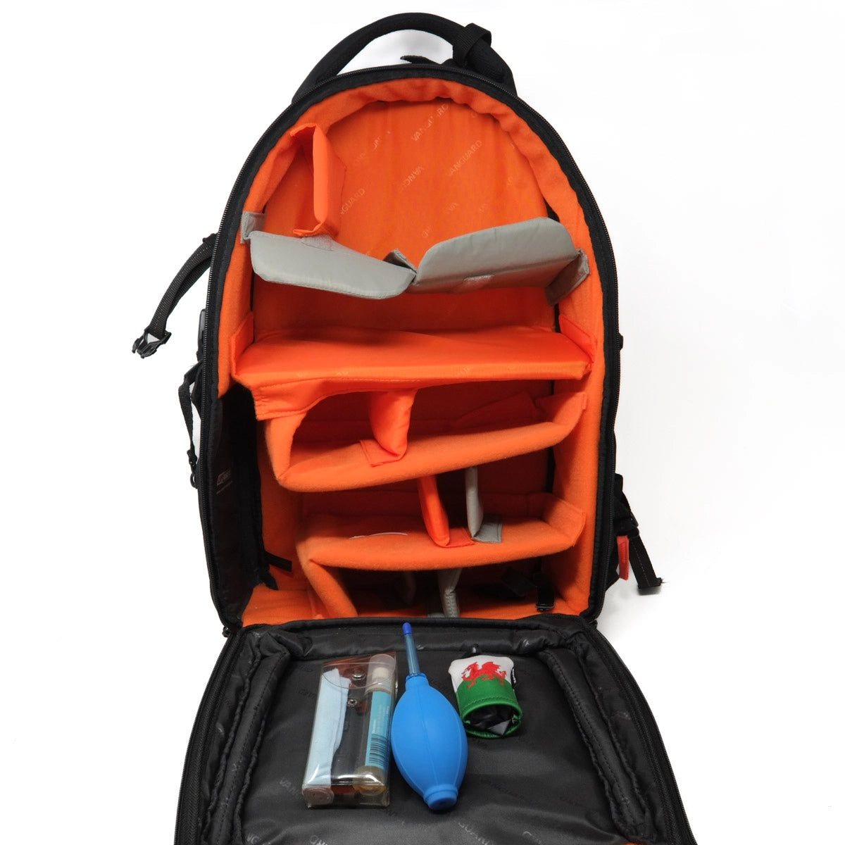 Open backpack with orange interior compartments and various items on a white background