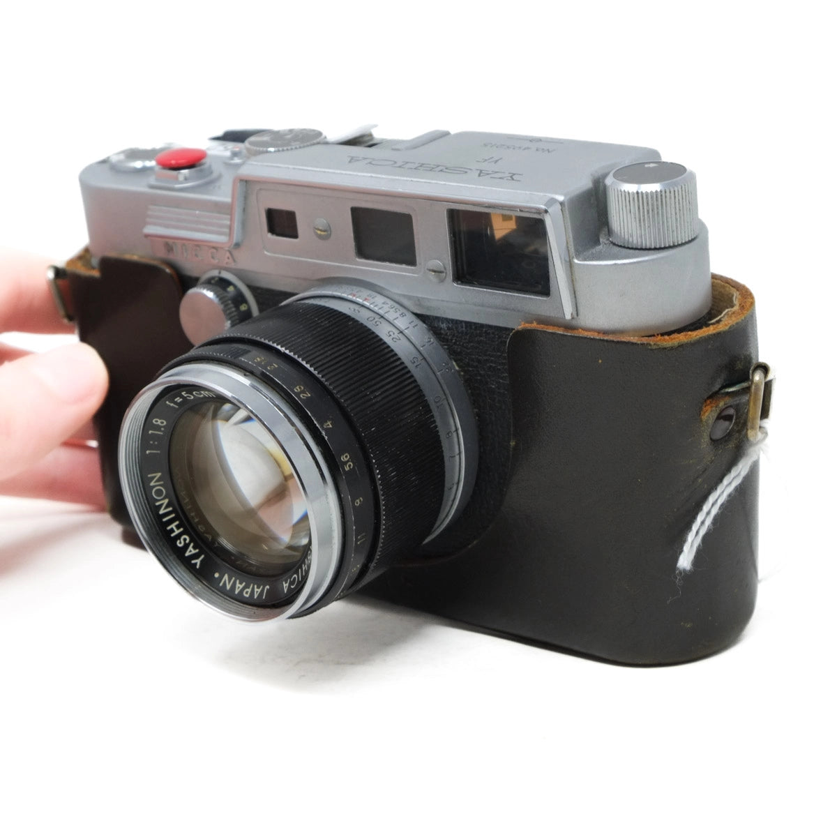 Vintage camera with a leather case held by a hand on a white background