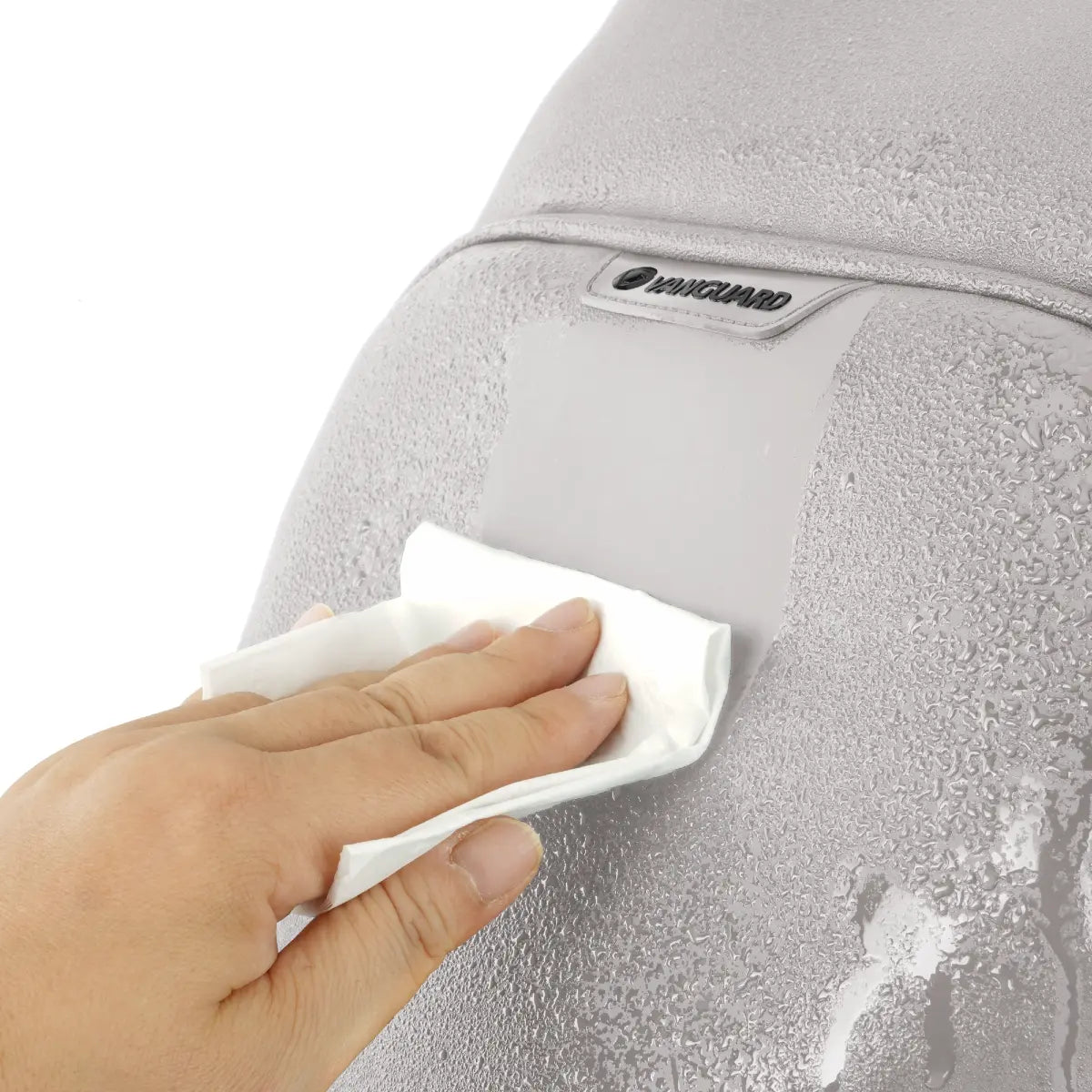 Hand using a white cloth to wipe a gray surface with a brand logo.