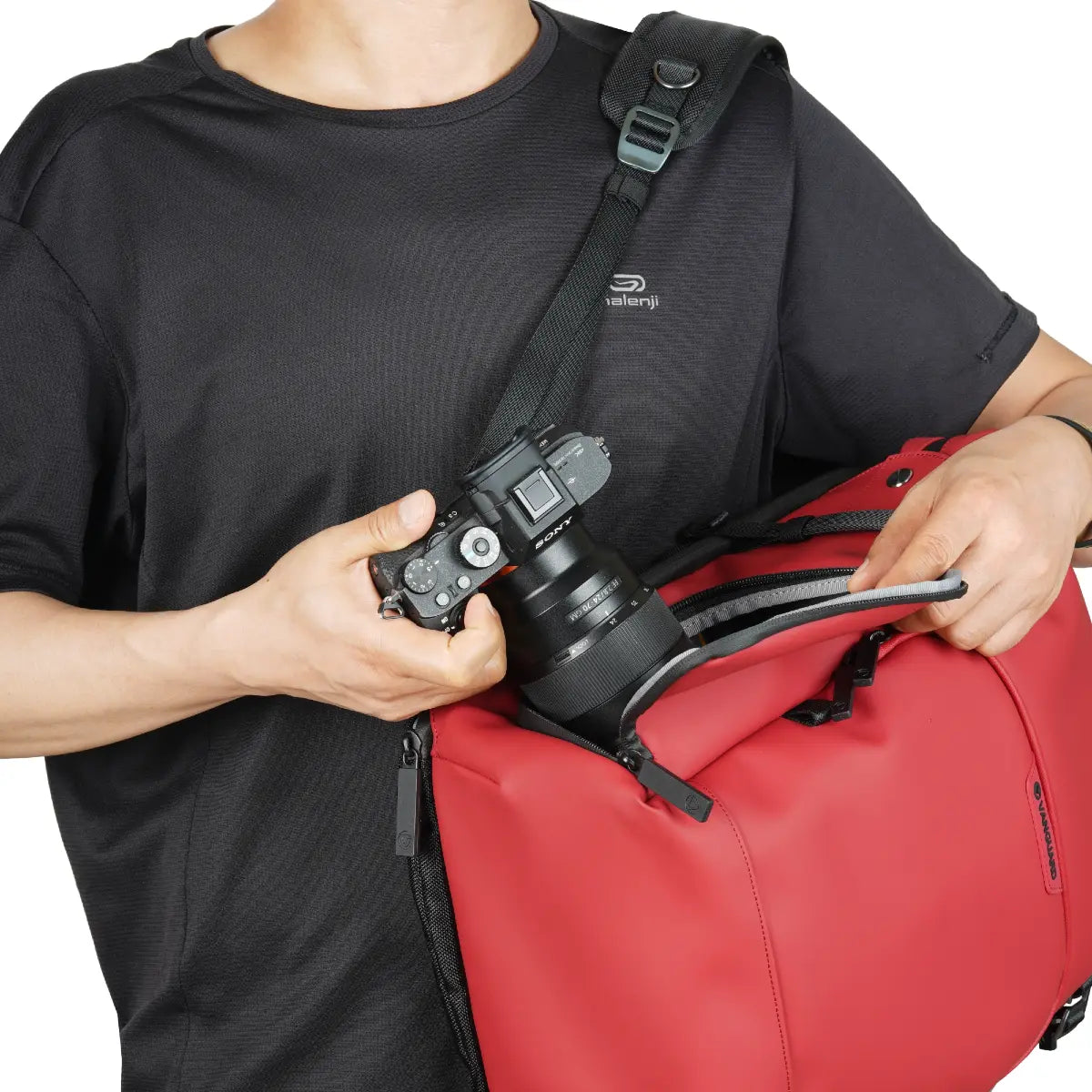 Person holding a camera and red bag with a black strap