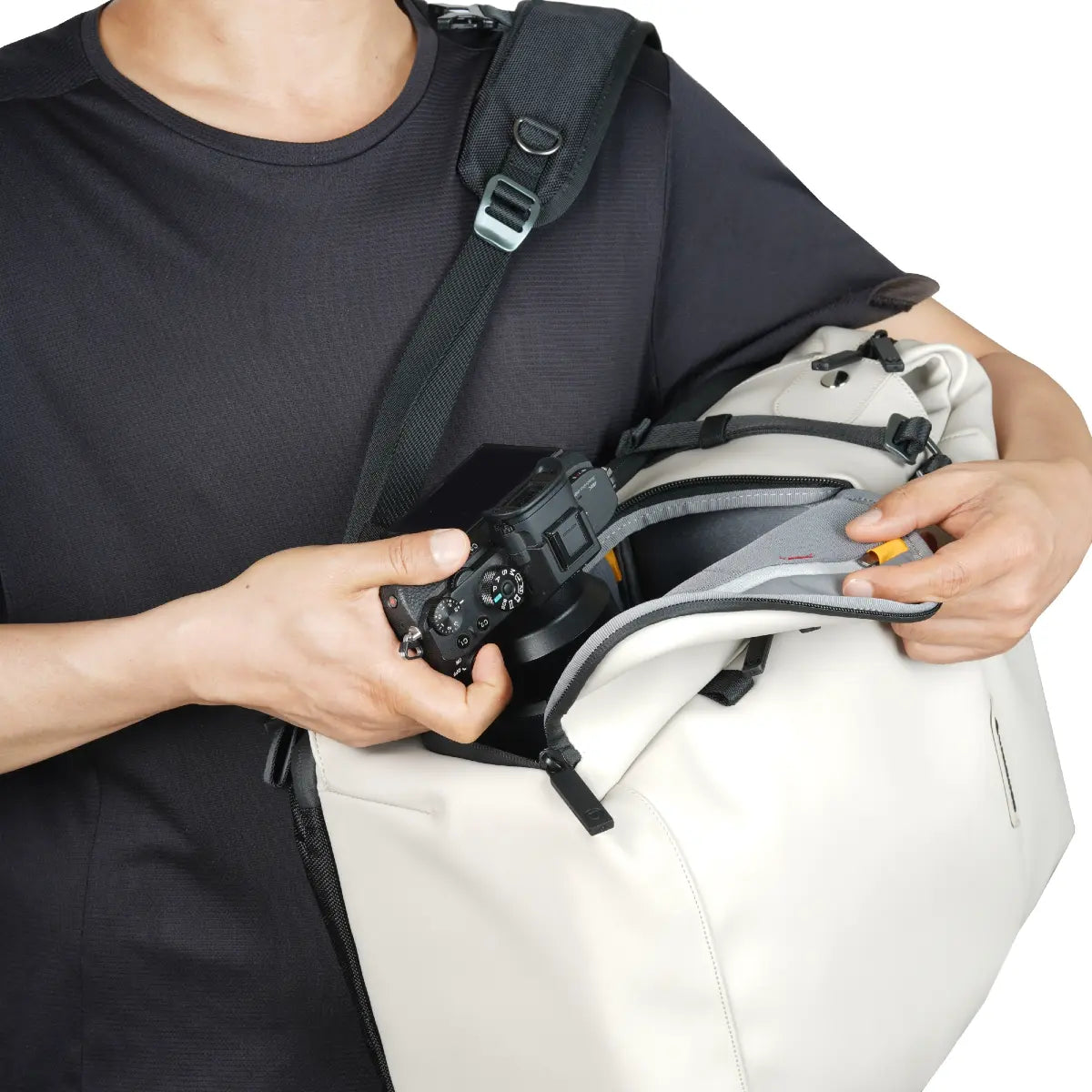Person holding a camera and a white bag with a black strap.