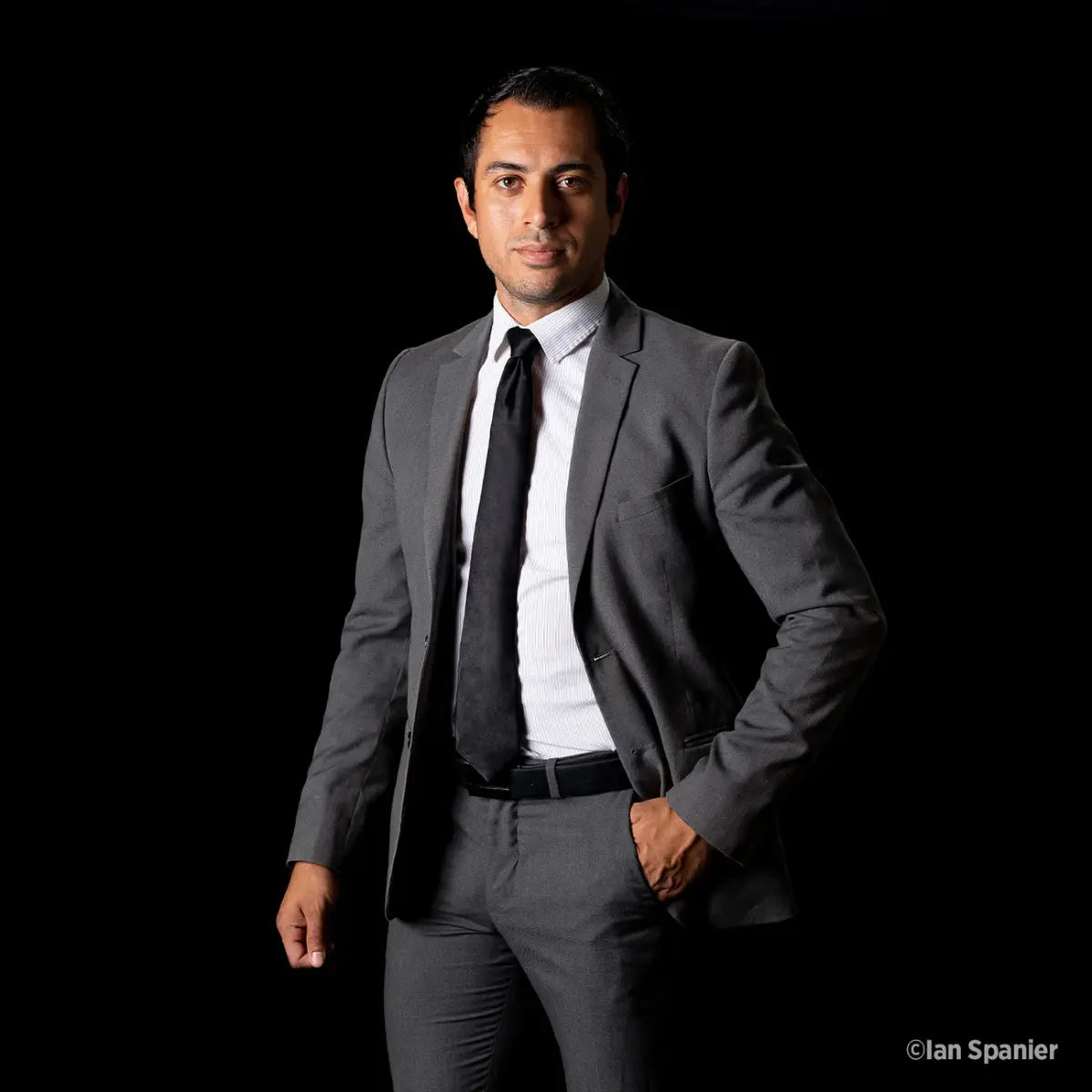 Man in a gray suit standing against a black background
