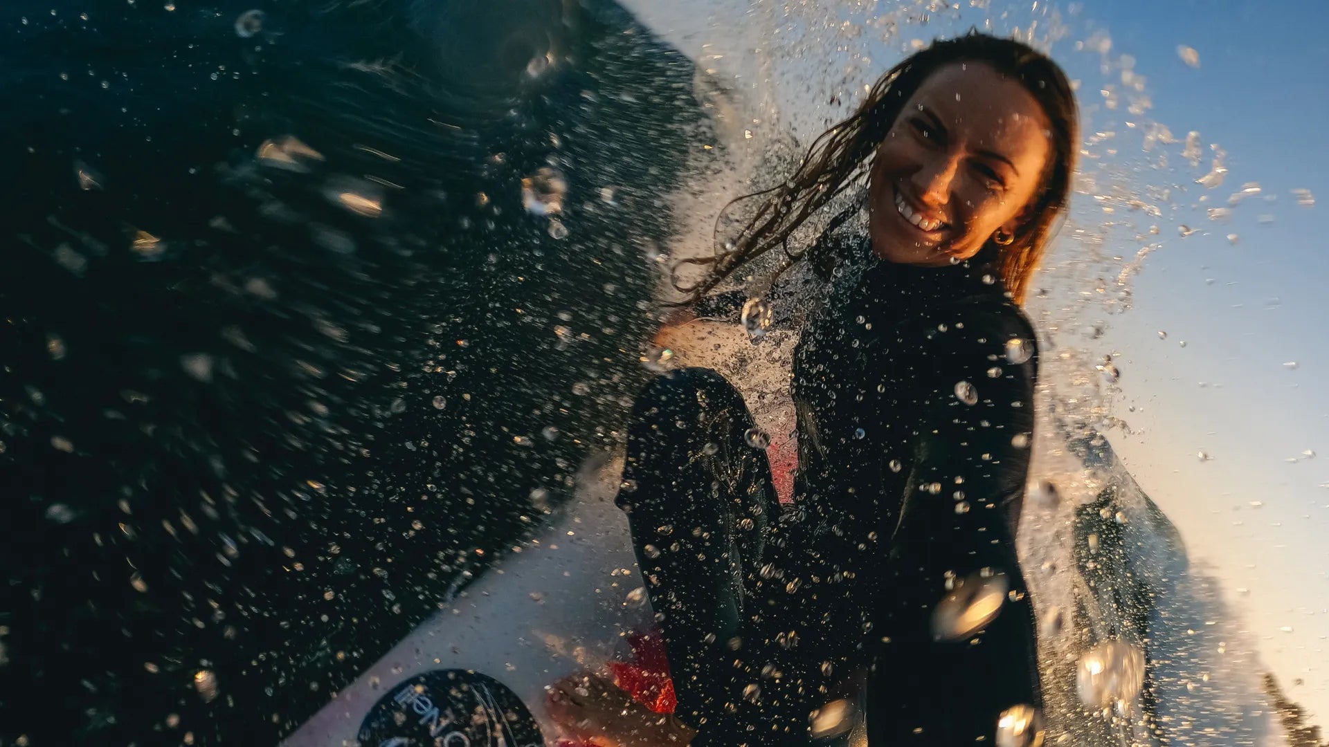 Action shot of the gopro in action in the water with a female surfer smiling whilst the waves splash around her