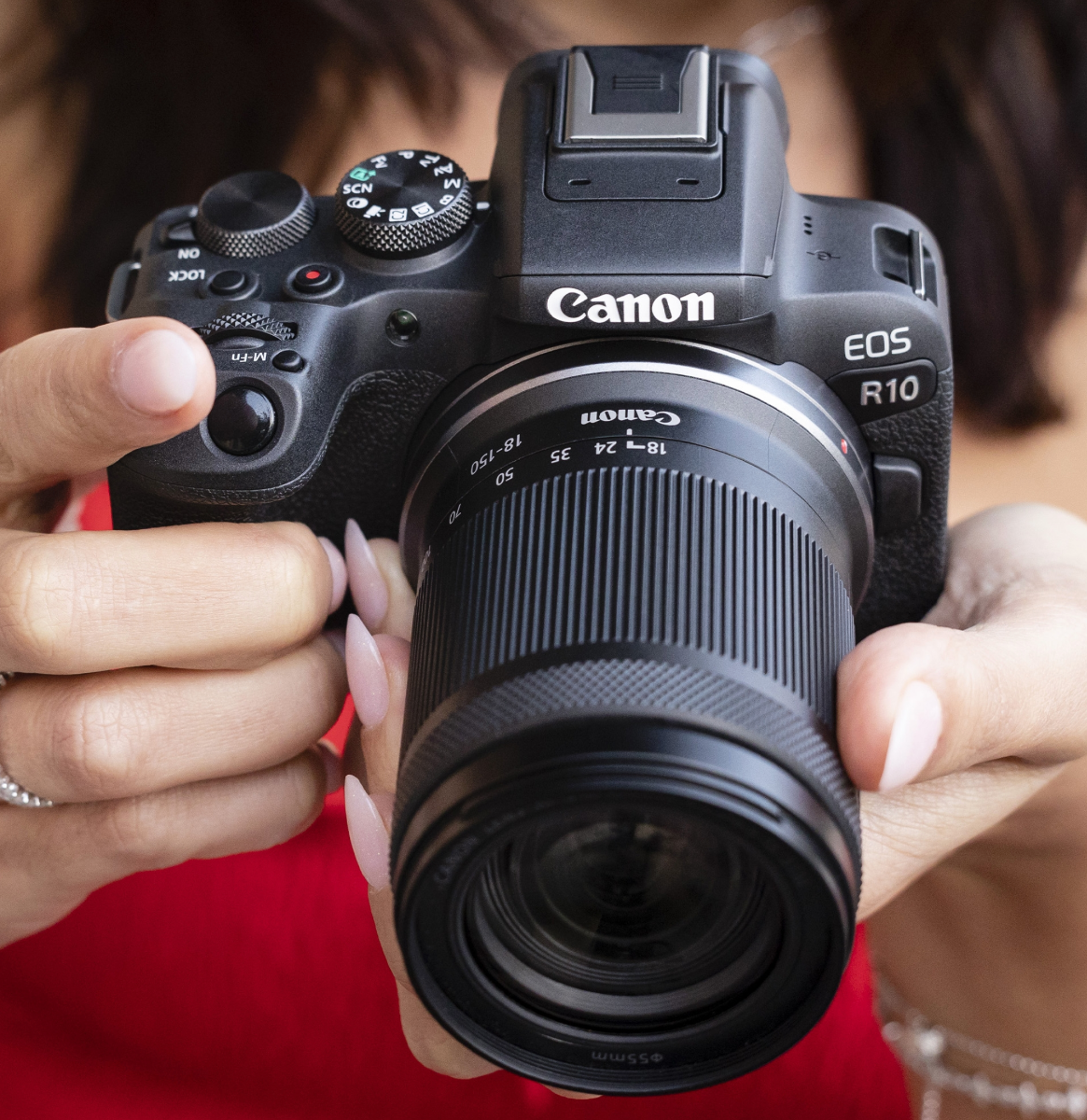 Canon EOS R10 Mirrorless Camera + RF-S 18-150mm F3.5-6.3 IS STM Lens Kit - Lifestyle Photo 1 - Close up of a lady holding the camera to show the scale of the product