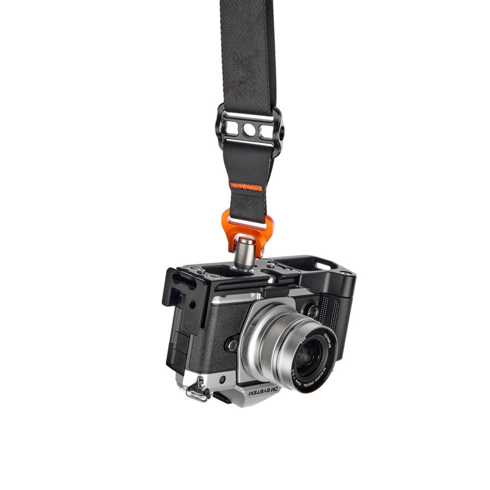 A black camera strap with an orange quick-release clip attached to the lens of a black and silver Fujifilm Instax Mini-L camera, shown against a plain white background.