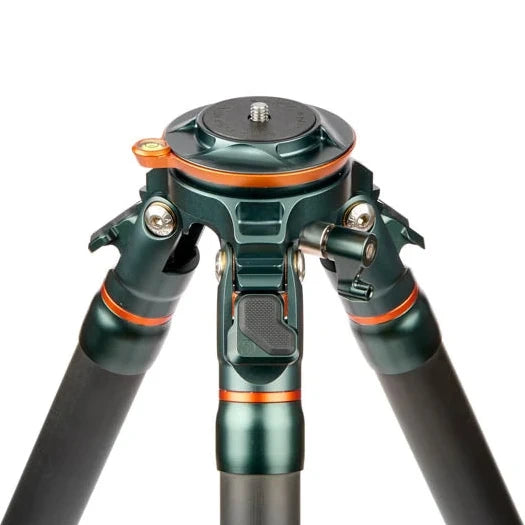 Close-up of a tripod head and lower legs in dark metallic green with orange accent rings, photographed on a clean white background.