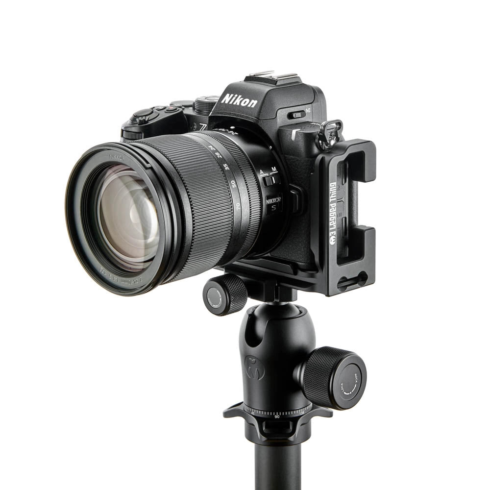 A Nikon mirrorless camera with a lens attached, mounted on a black tripod and a vertical bracket, shown against a plain white background.