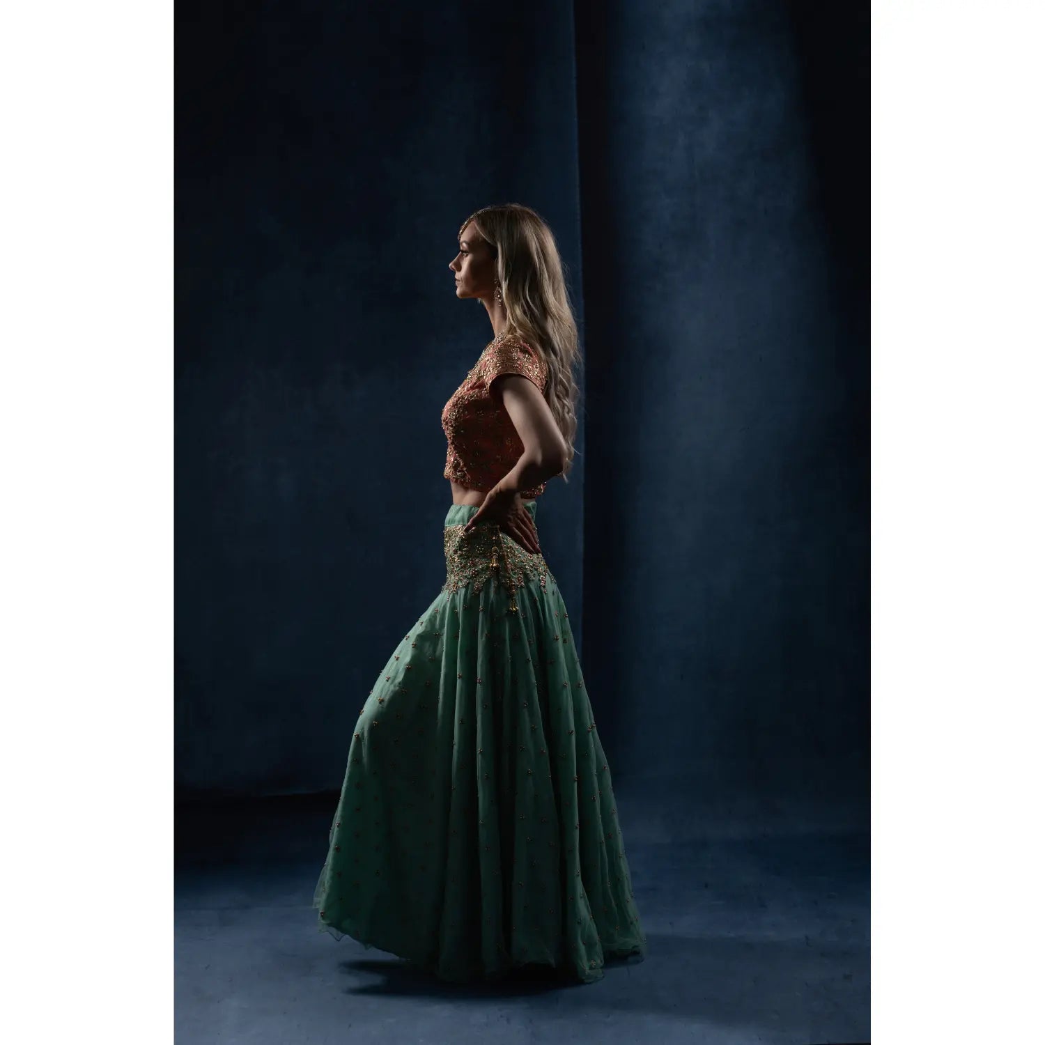 Woman in a green dress standing against a dark background