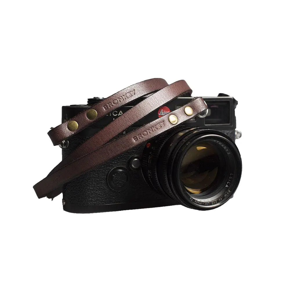 Camera with a brown leather strap on a white background