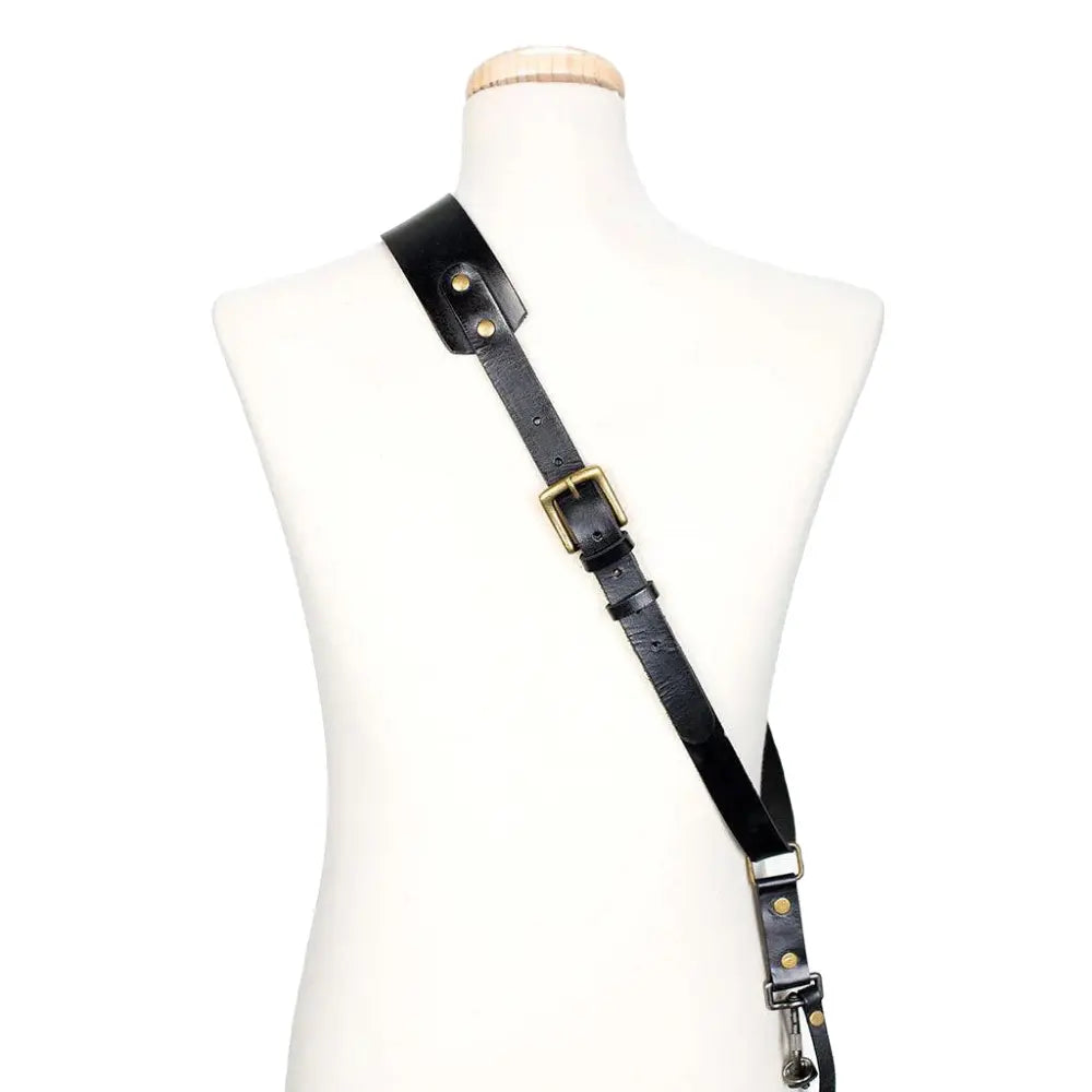 Black leather strap with gold buckles on a mannequin bust against a white background