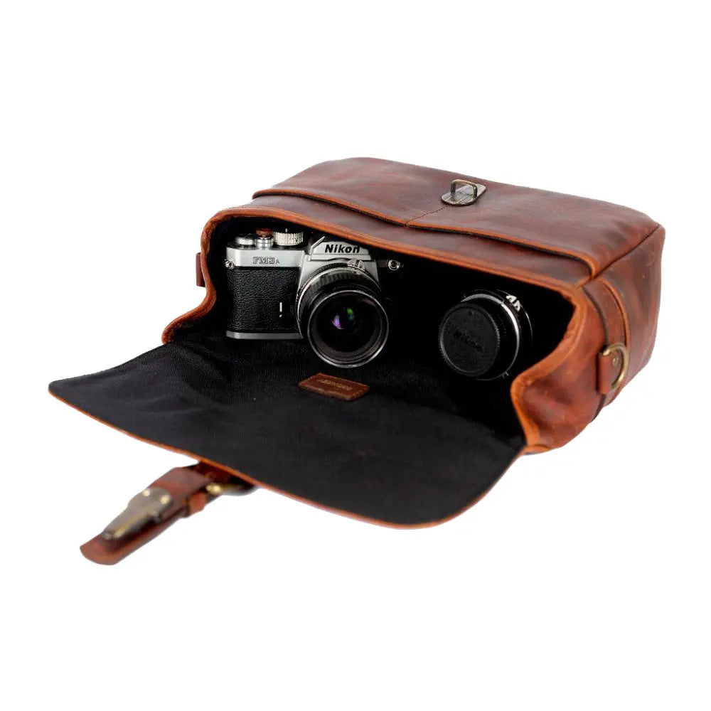 Brown leather camera bag with a Nikon camera inside on a white background