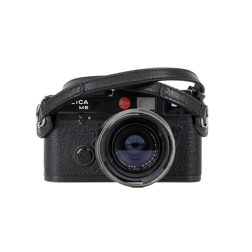 Black camera with leather strap on a white background