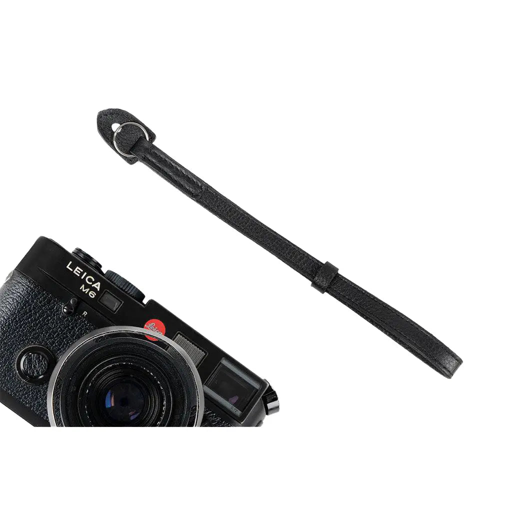 Leica camera with a black camera strap on a white background