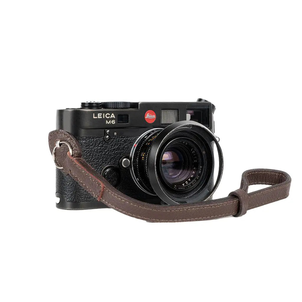 Leica camera with a brown leather strap on a white background