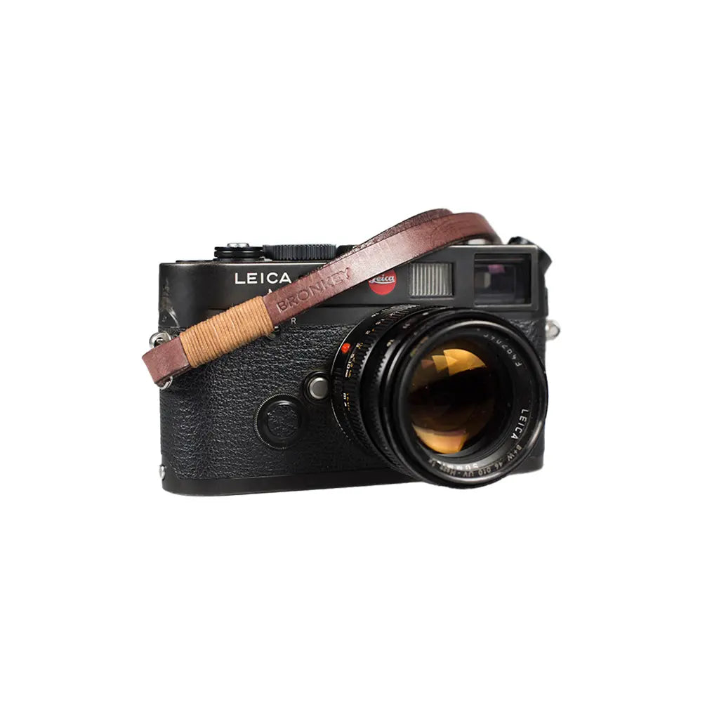 Leica camera with a brown leather strap on a white background