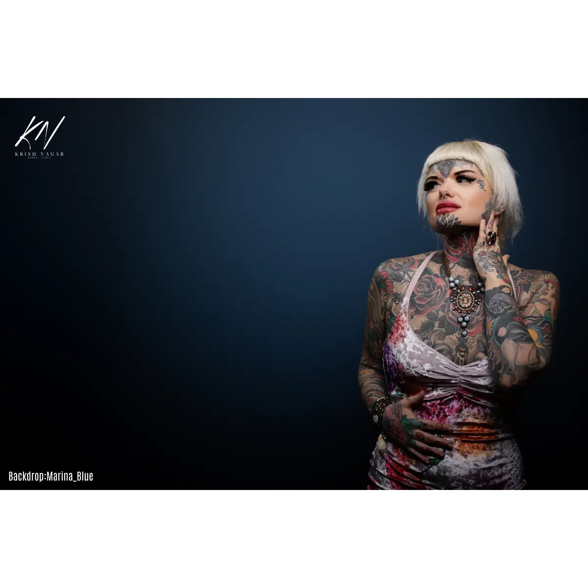 Woman with tattoos against a dark blue background