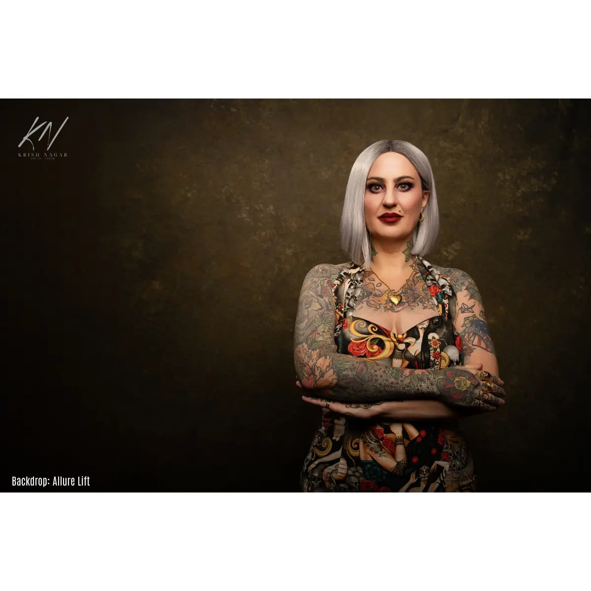 Woman with tattoos and colorful clothing against a dark background