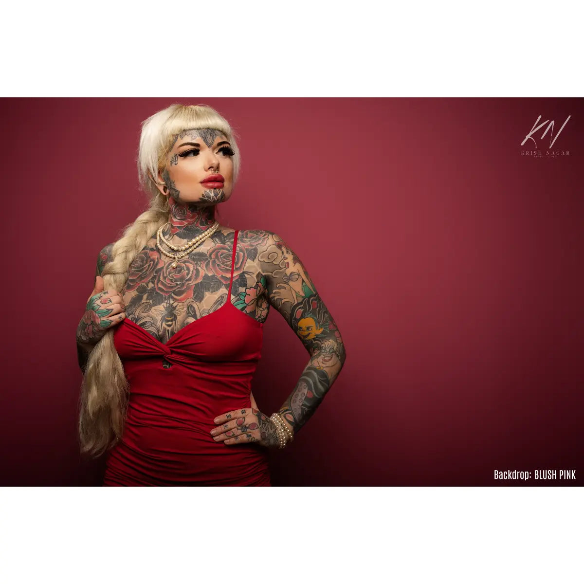 Woman with tattoos wearing a red dress against a red background