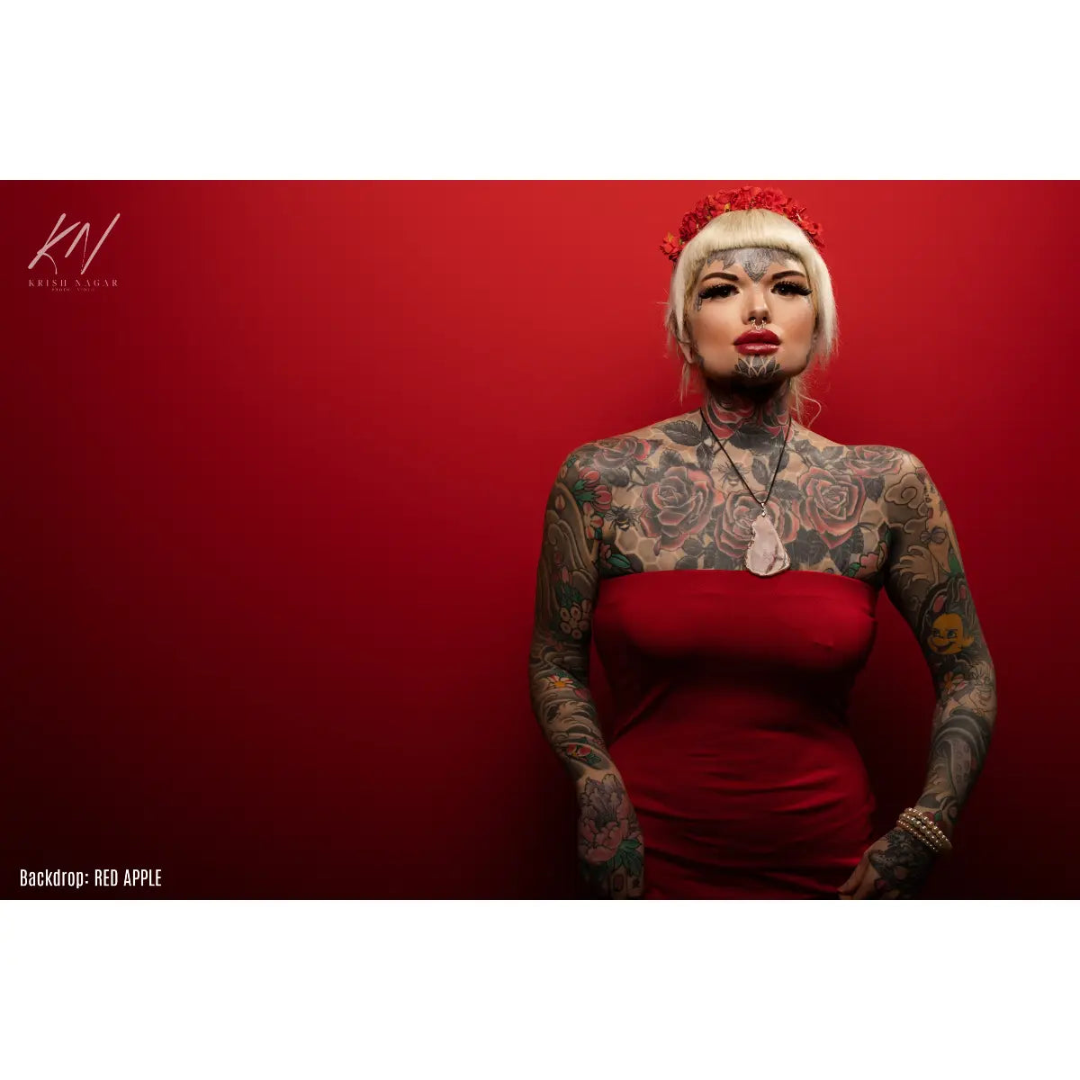 Woman with tattoos wearing a red dress against a red background