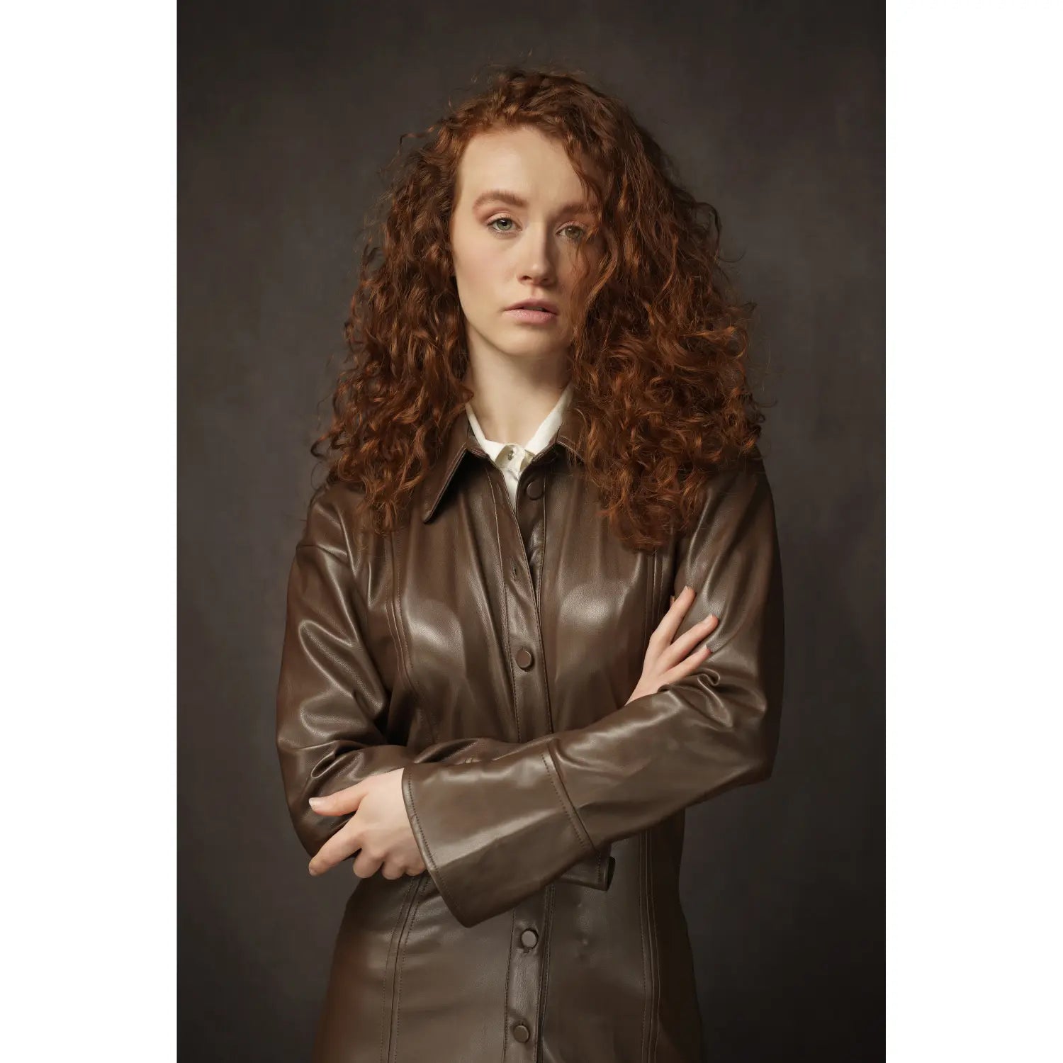 Woman wearing a brown leather jacket against a dark background