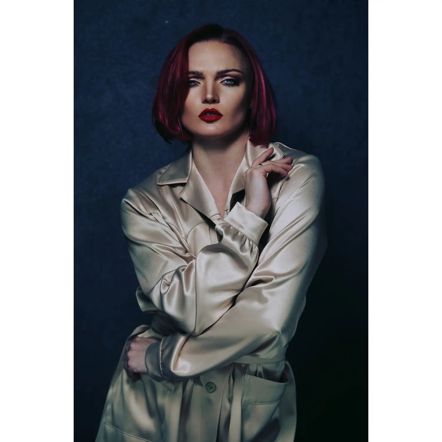 Woman with red hair wearing a beige trench coat against a dark background
