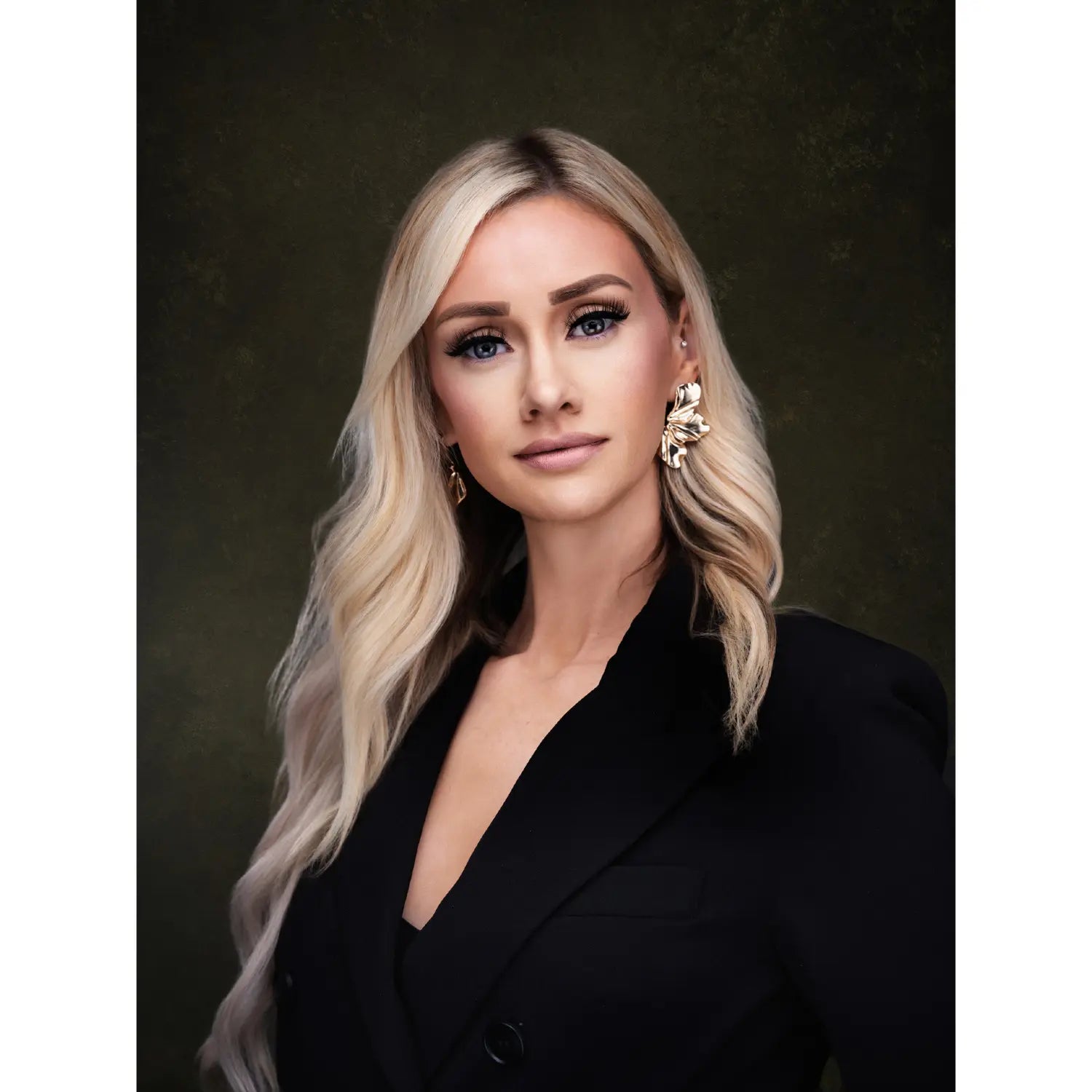 Woman with blonde hair and black outfit against a dark background