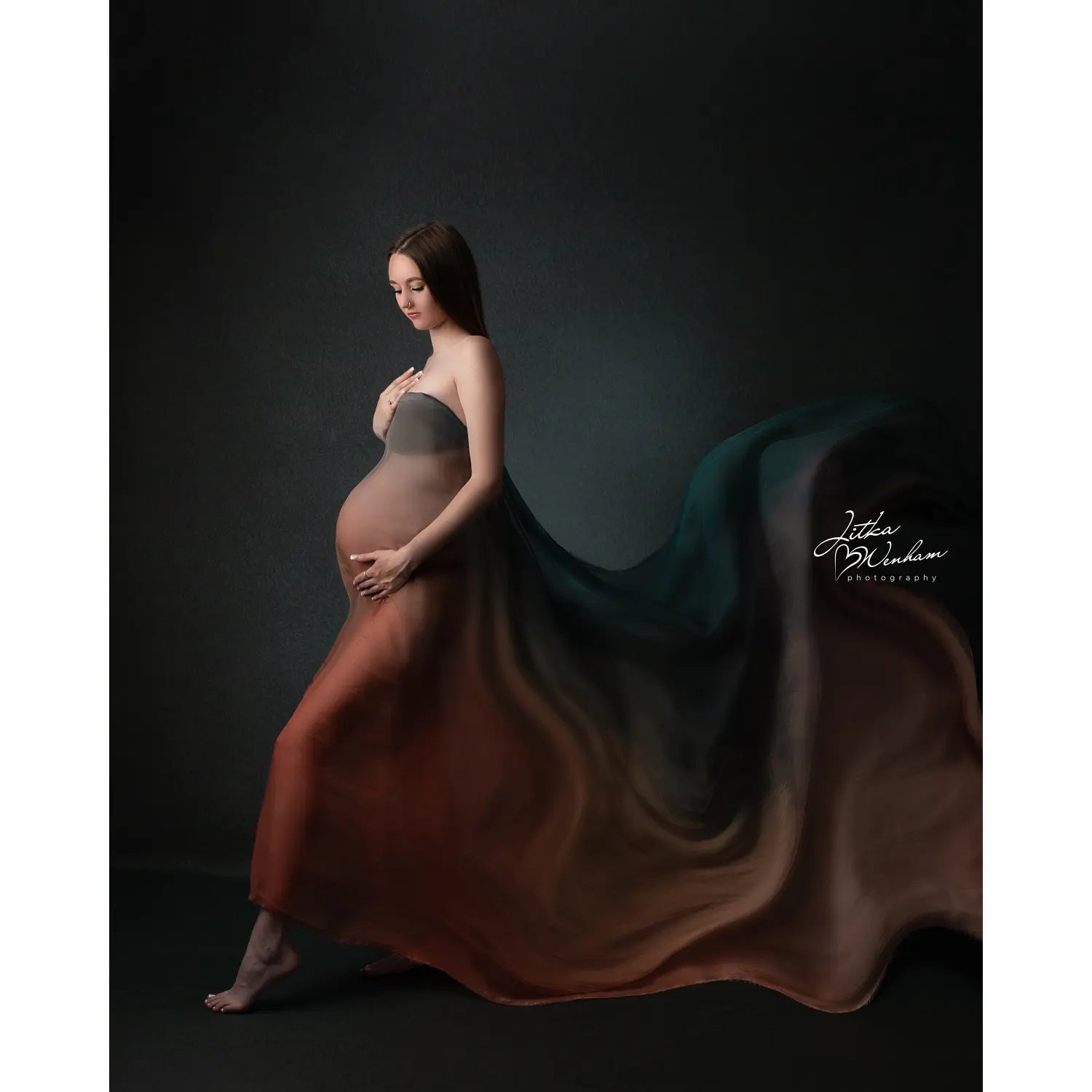 Pregnant woman in a flowing dress against a dark background