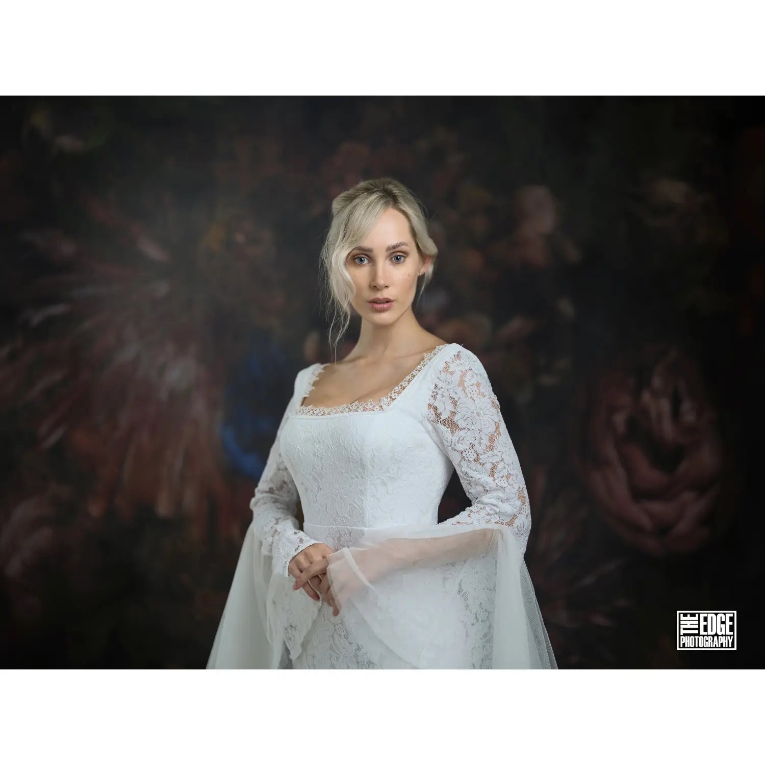 Woman in a white lace dress against a dark, artistic background