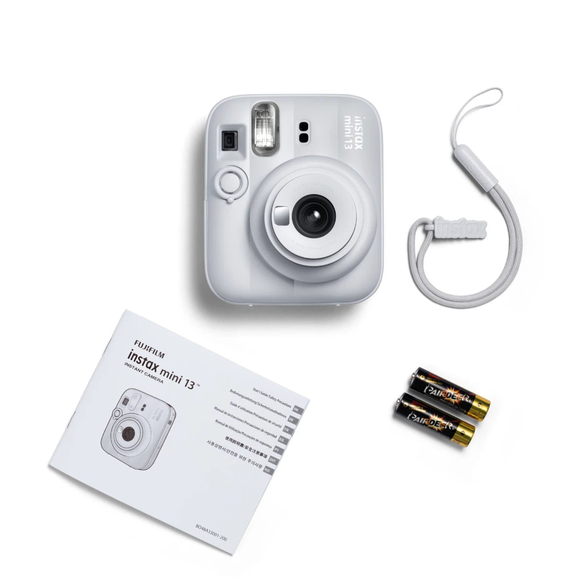 Fujifilm Instax mini 13 instant camera with strap, batteries, and manual on a white background