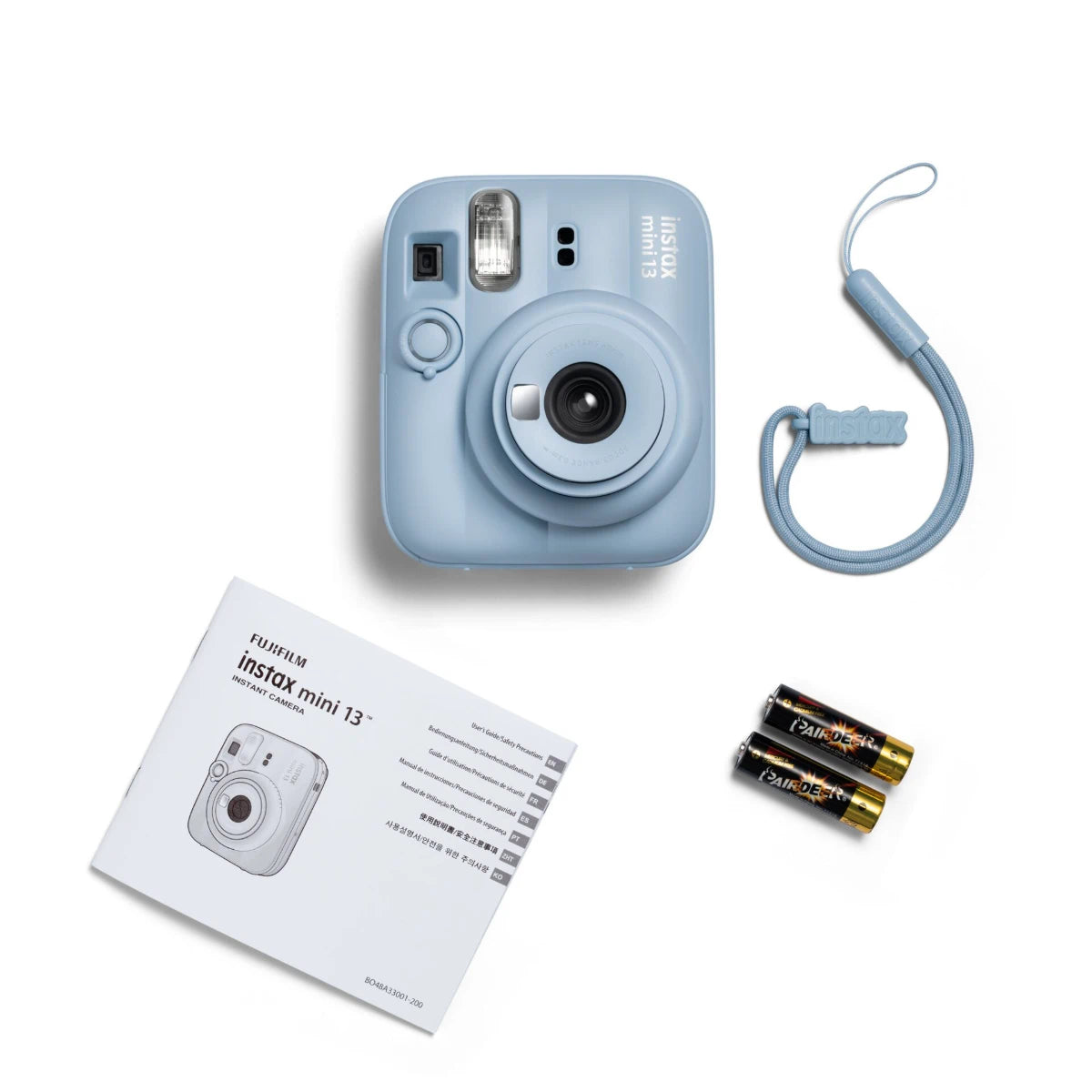 Blue instant camera with strap, batteries, and manual on a white background