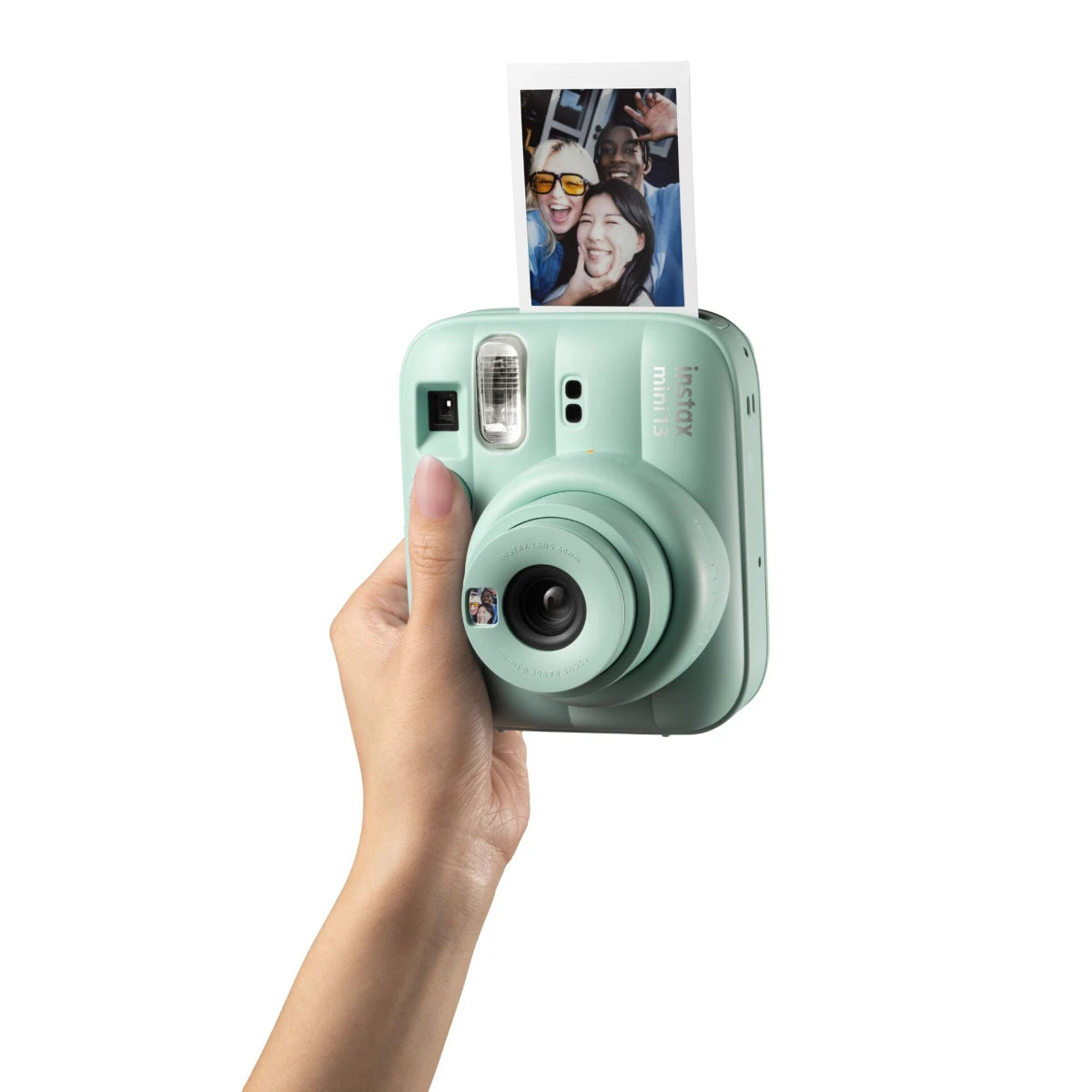Mint green instant camera held by a hand with a photo of people on the screen.