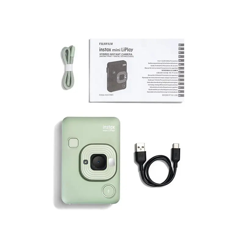 Mint green instant camera with USB cable, power adapter, and user manual on a white background
