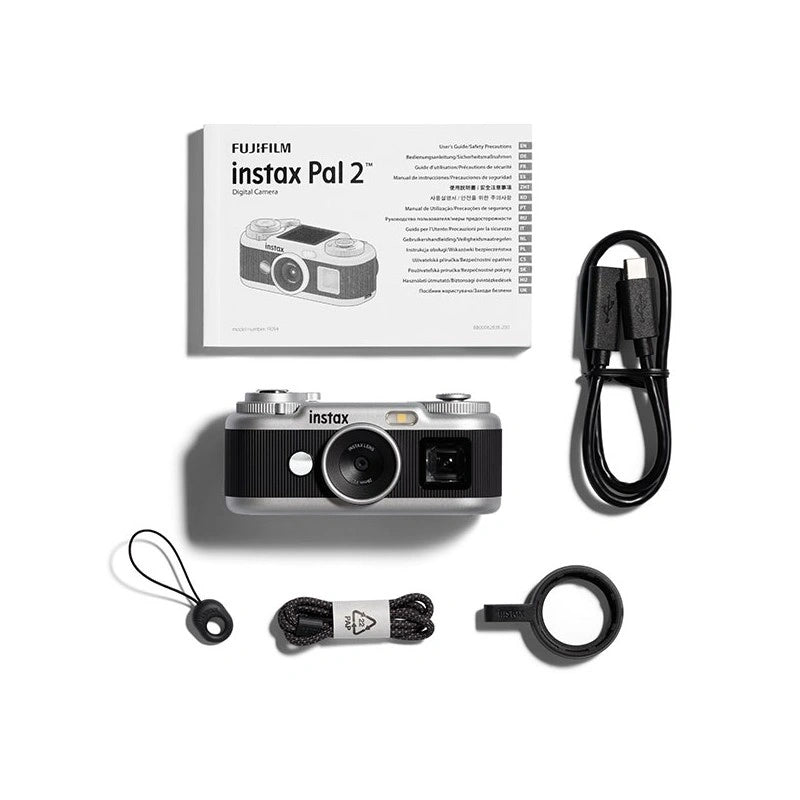 Fujifilm Instax Pal 2 digital camera kit on a white background, including the camera body, retail box, USB cable, strap, cord, and ring light.