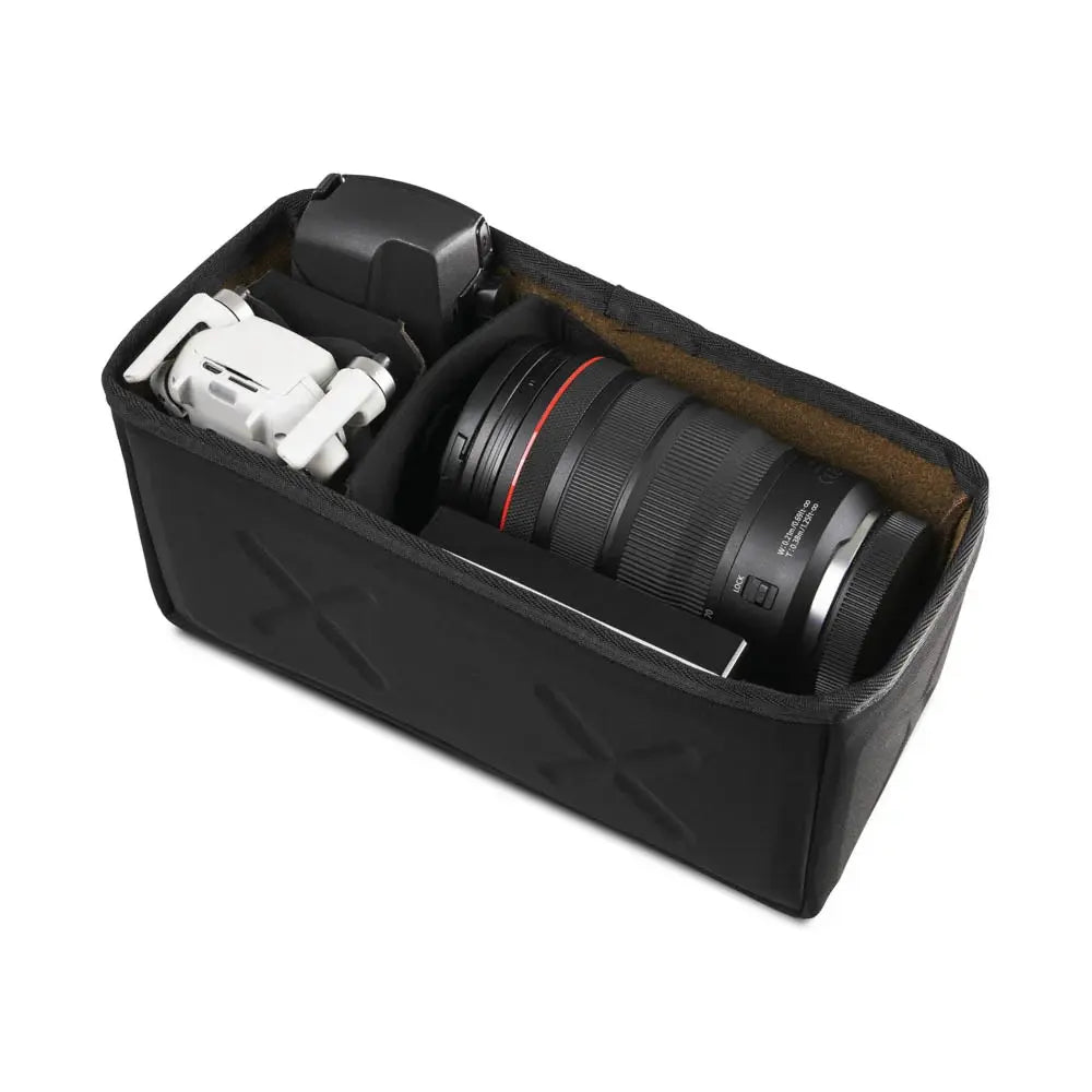 Black camera lens and accessories in a compartmentalized black case on a white background