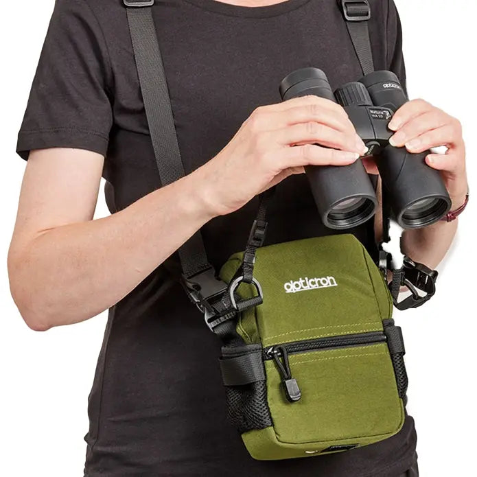 Person holding binoculars with a green backpack featuring 'Optronics' branding.