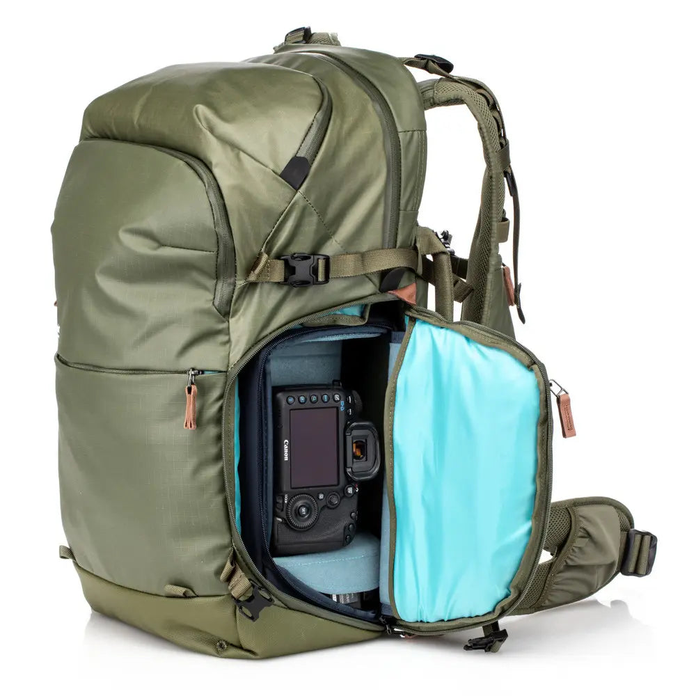 Green backpack with a camera inside on a white background