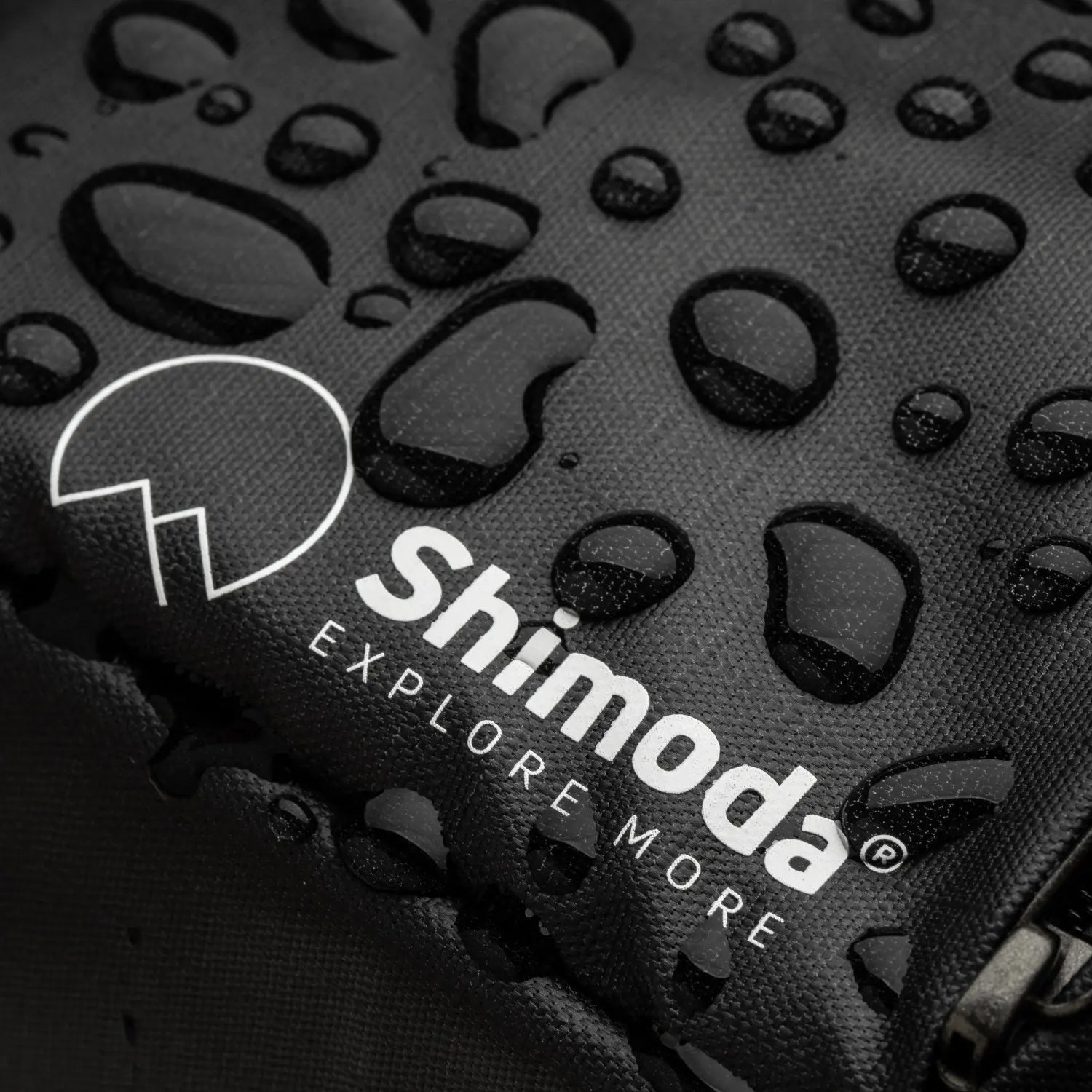 Shimoda logo on a textured black surface with water droplets.