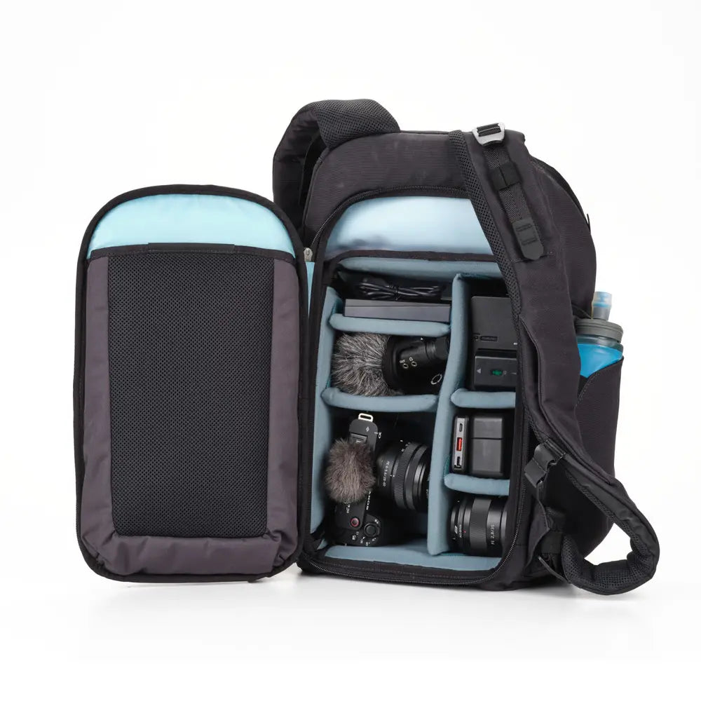 Camera backpack with compartments filled with photography equipment on a white background