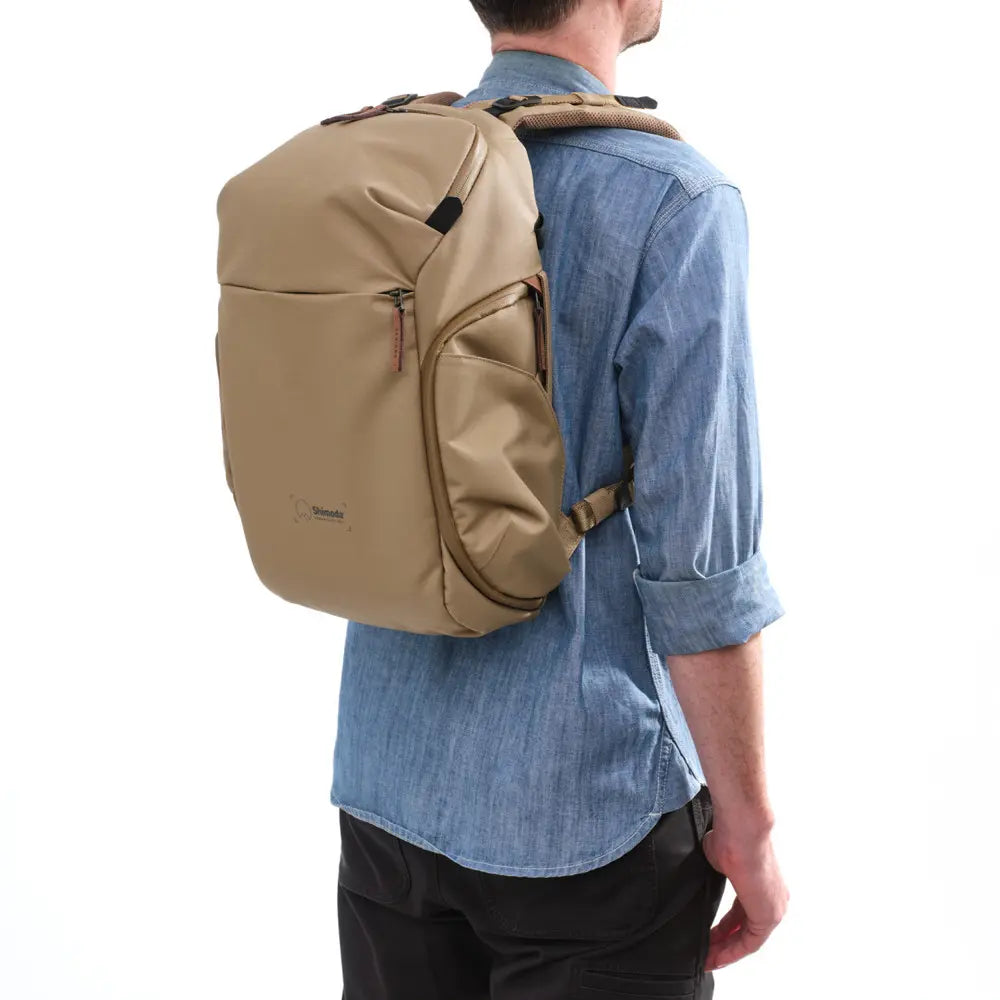 Person wearing a beige backpack on a white background