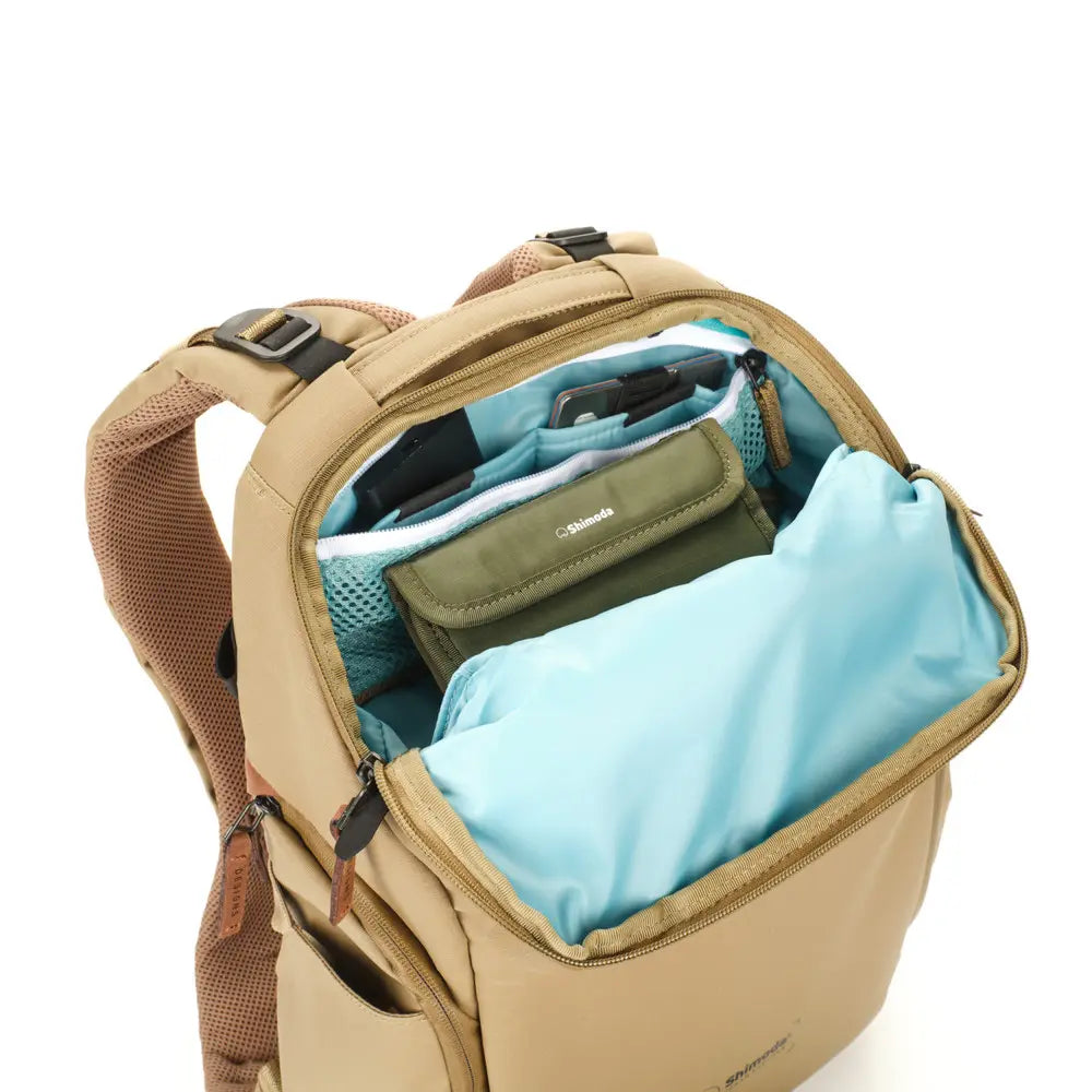 Open beige backpack with blue and green interior on a white background