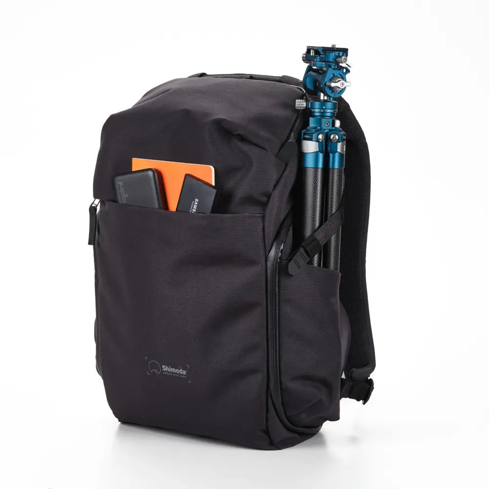 Black backpack with a camera tripod and accessories on a white background