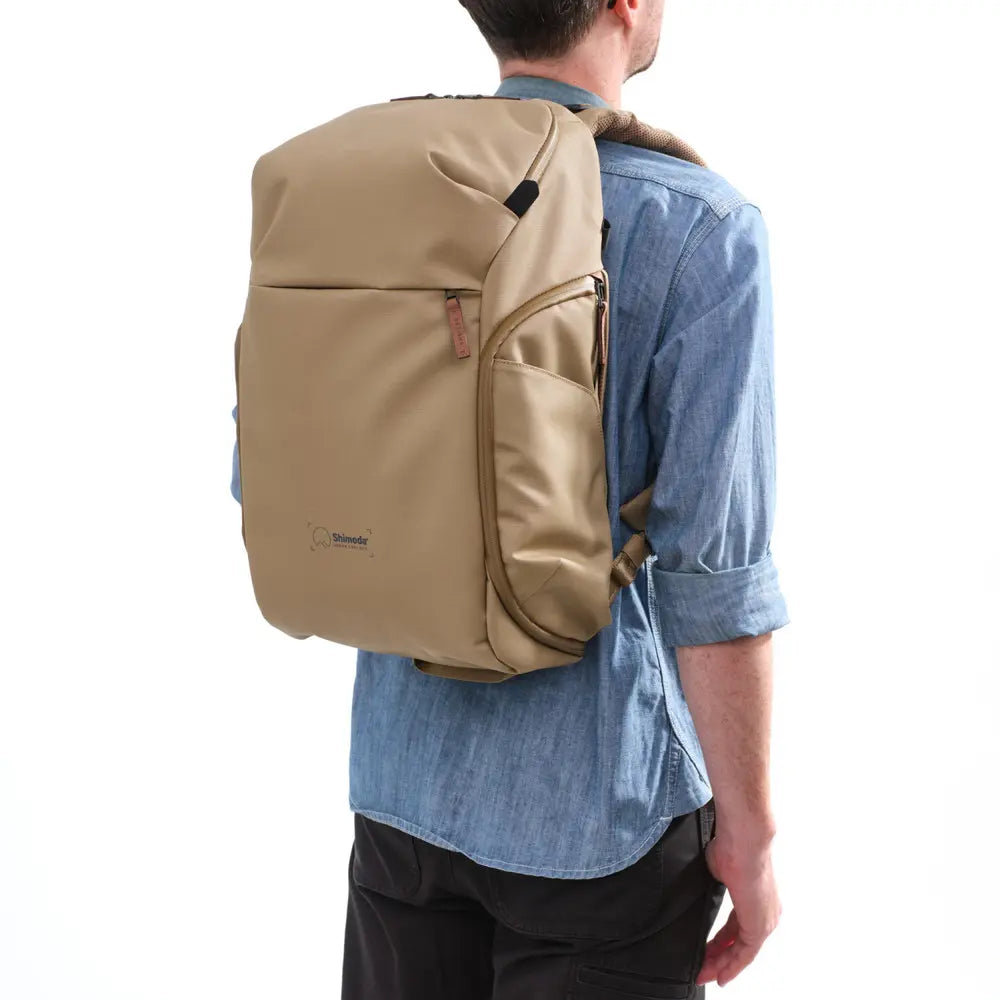 Person wearing a beige backpack on a white background