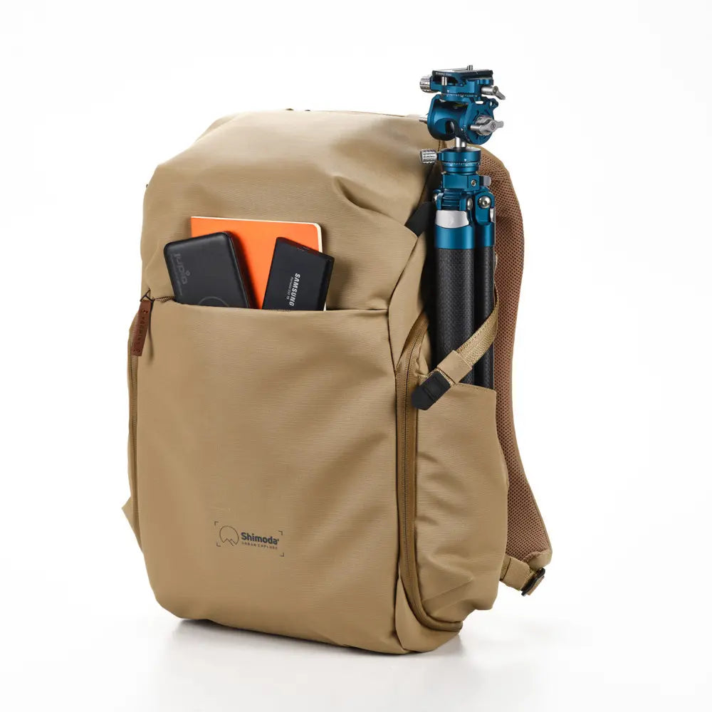 Beige backpack with a camera tripod and accessories on a white background
