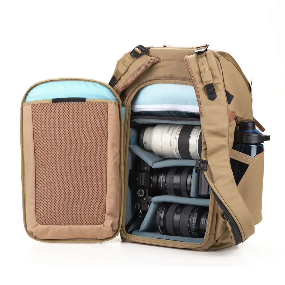 Open beige backpack with camera equipment on a white background
