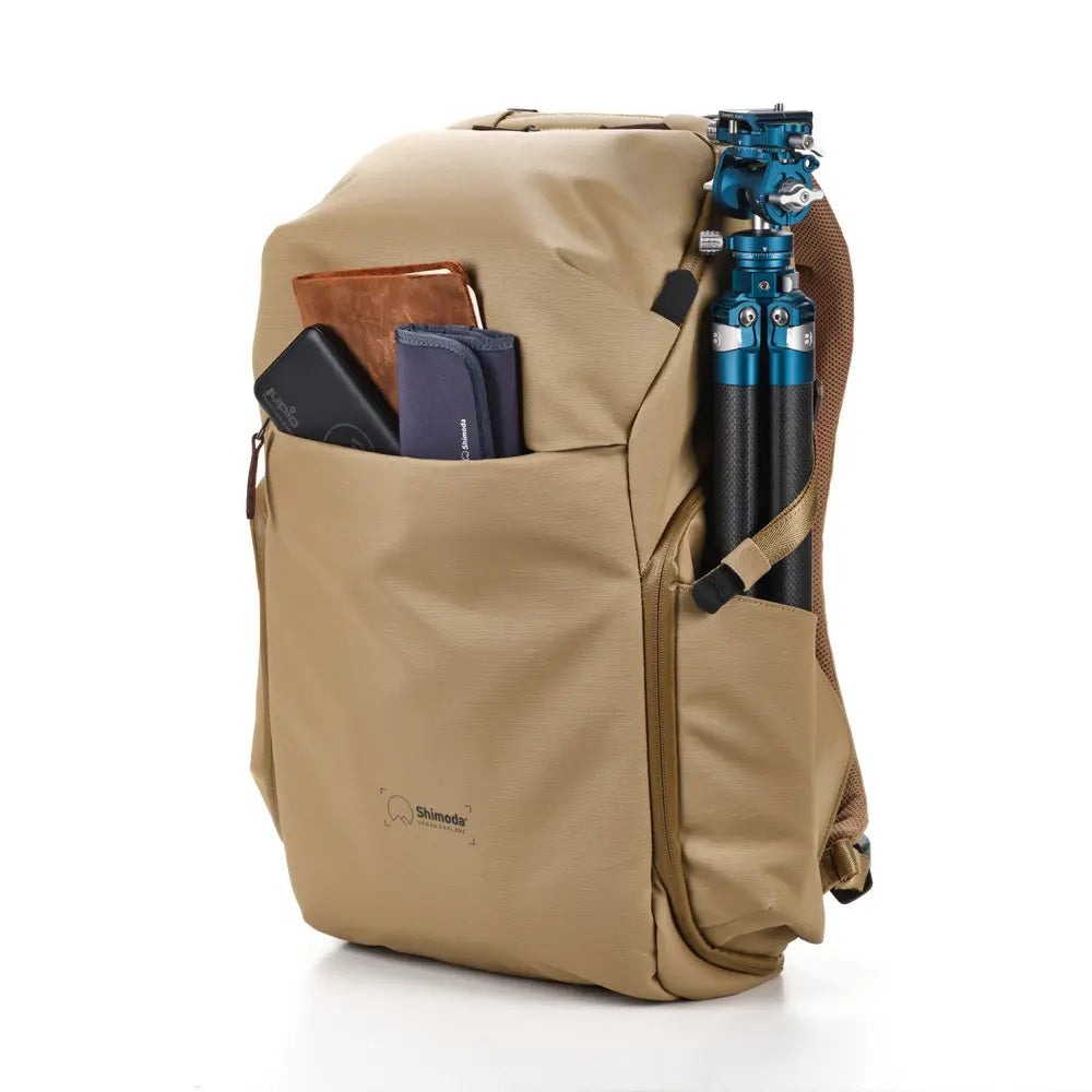 Beige backpack with compartments containing electronic devices on a white background
