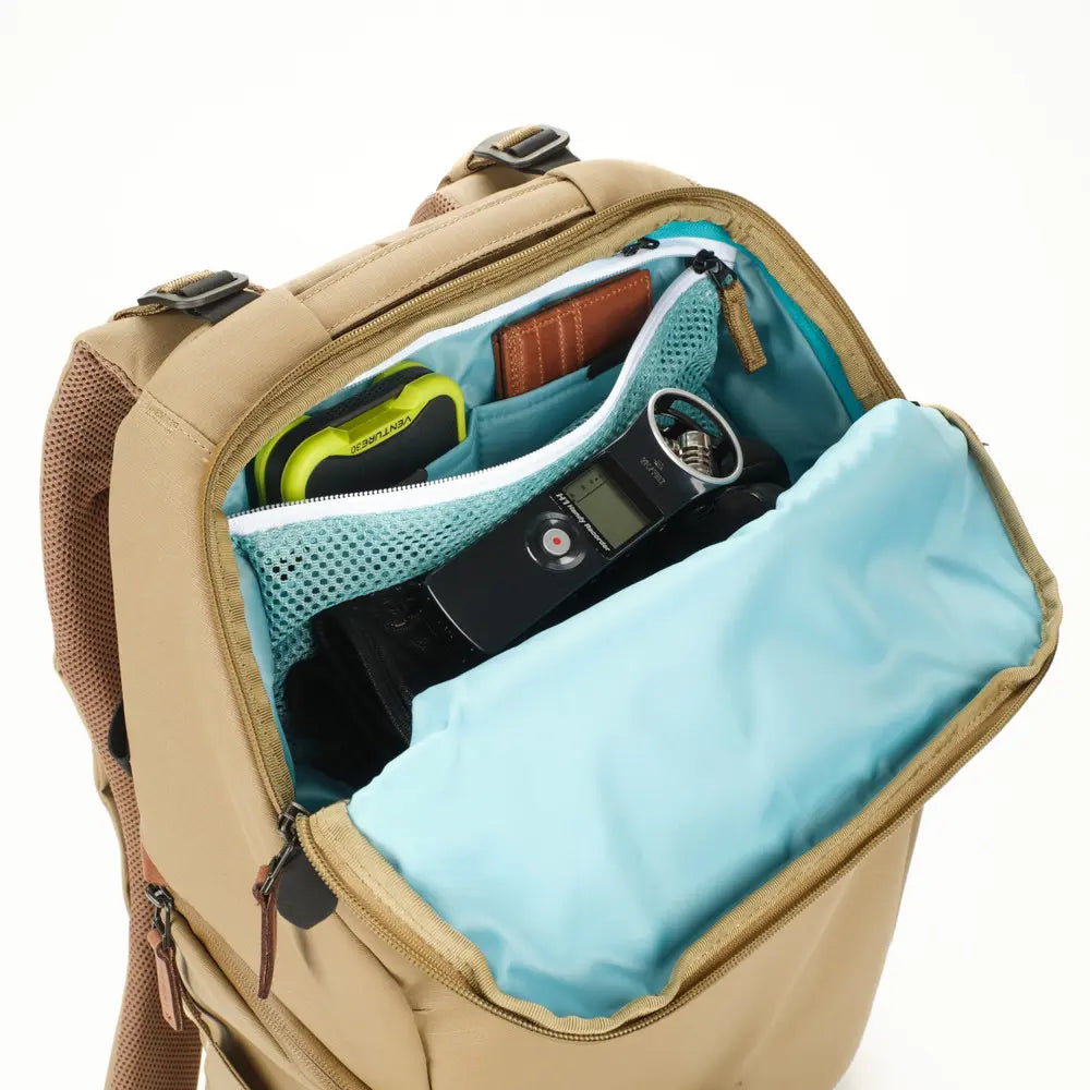 Open beige backpack with items inside on a white background