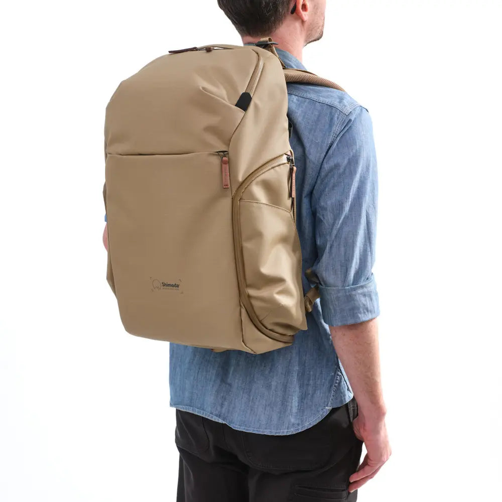 Person wearing a beige backpack on a white background